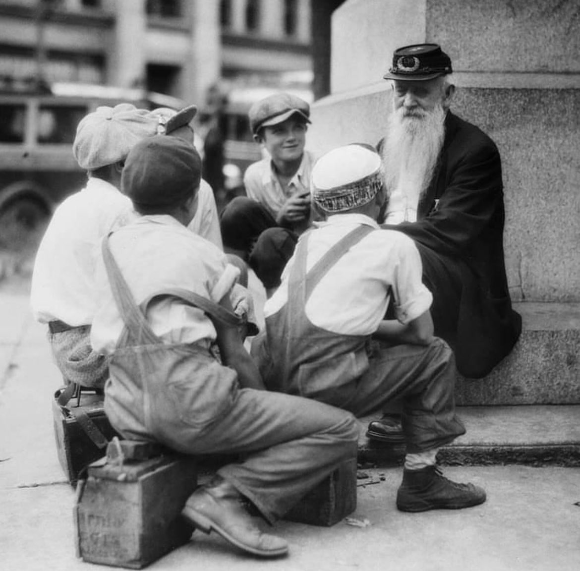 A group of shoe shine boys gather around an old Civil War veteran to listen to his war stories, 1935.

The Civil War veteran in the photograph is wearing the cap of the Grand Army of the Republic (GAR), which was the largest Union veterans' organization founded in 1866. The…