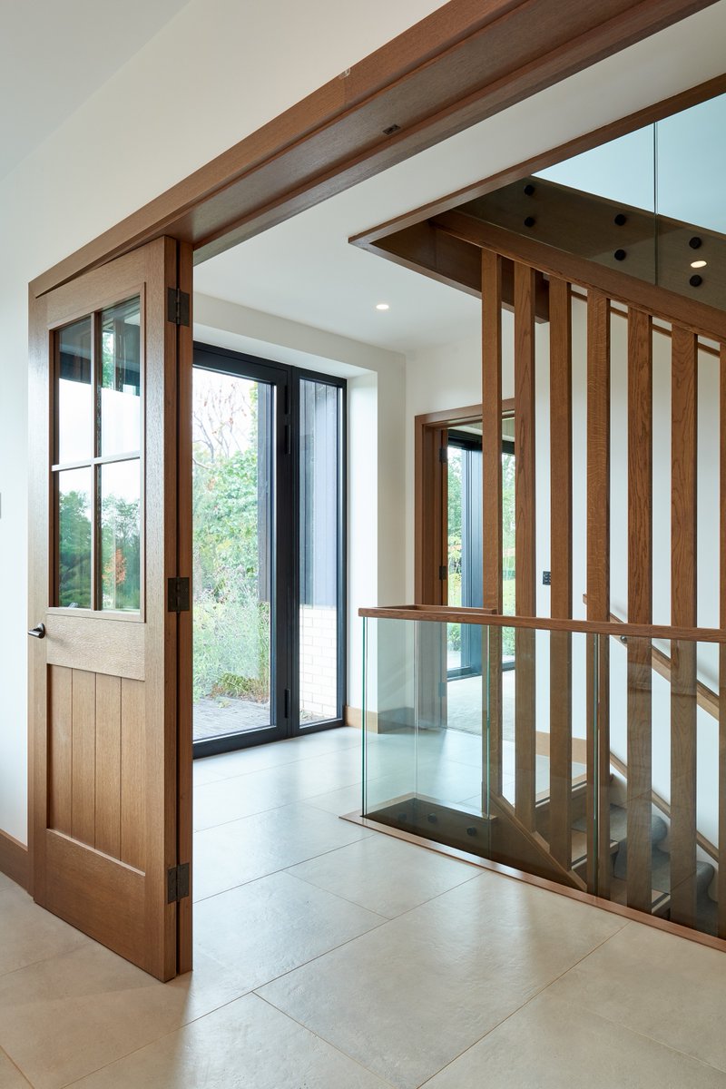 Project 6968. Grey stained slip-matched oak furniture with a factory sprayed matt white island and "goal posts" framing,  incorporating a secret door through to the utility and boot room. #kitchendesign #kitchendesignideas #kitchendesign #kitchenmanufacturers #bespokekitchens