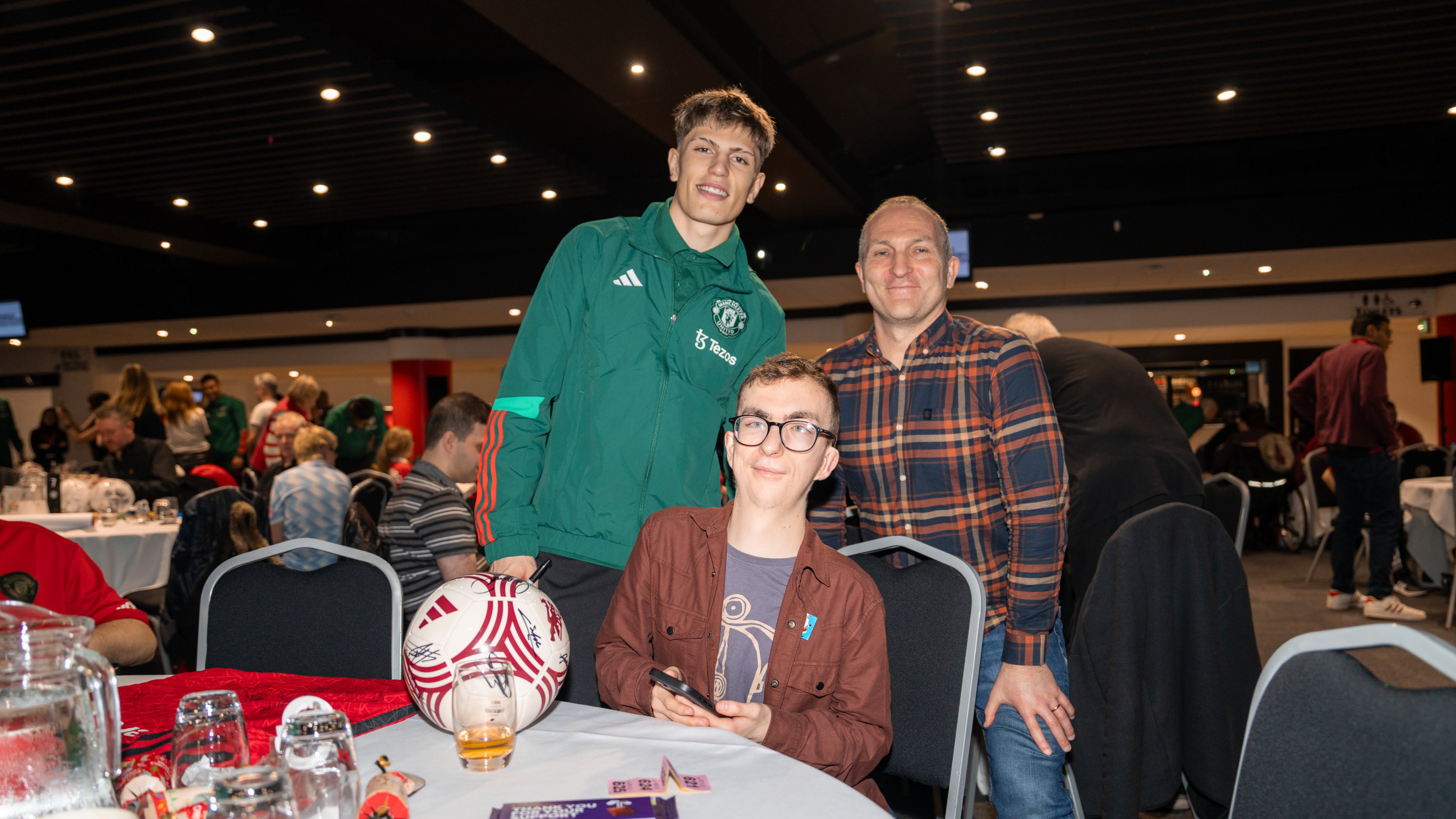 Alejandro Garnacho takes a photo with two fans at the MUDSA Christmas party.