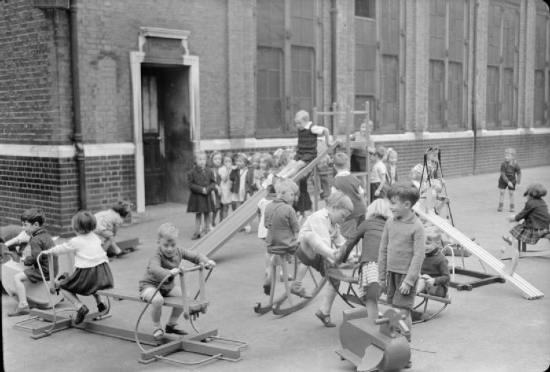 In the playground of an infant school in north London, young children play on the slides, see-saws and rocking horses made by the boys of Medburn Road School from salvaged materials. 1943

#Britishhistory #london #vintageLondon #londonhistory