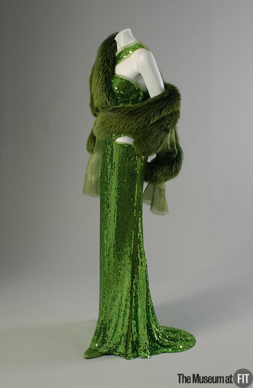 From Tom Ford's last collection for Gucci, this 2004 acid green sequin gown and fur wrap embodies the sex appeal of Tom Ford designs, an appeal which helped to revive Gucci during the 1990s. Read more! fashionhistory.fitnyc.edu/2004-ford-gucc…