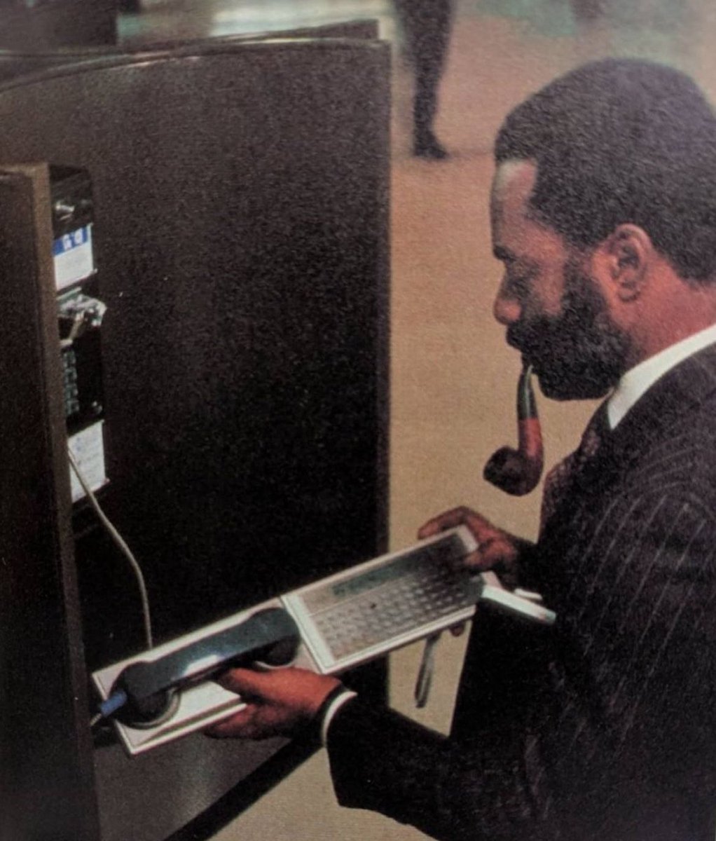 A traveling executive checks his email from his office electronic mail system through a Panasonic RL-H1400 hand held computer and a RL-P4001 Acoustic modem at a public telephone, early 1980s.

The Panasonic RL-H1400 was a hand held computer that was first introduced in 1982 and
