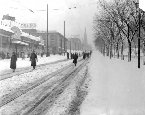 COnassis's tweet image. Pedestrians walk on Colfax Avenue at Broadway after a snowstorm in Denver, Colorado. The Cathedral of the Immaculate Conception is in the distance.  (1912-1920?)