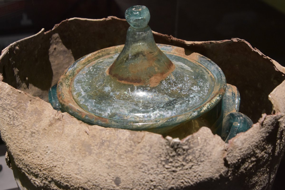 L'urna verde chiaro, con due manici a forma di "M", coperta da un coperchio anch'esso in vetro sigillato con malta di calce, si trova all'interno di un contenitore metallico in lega di piombo.