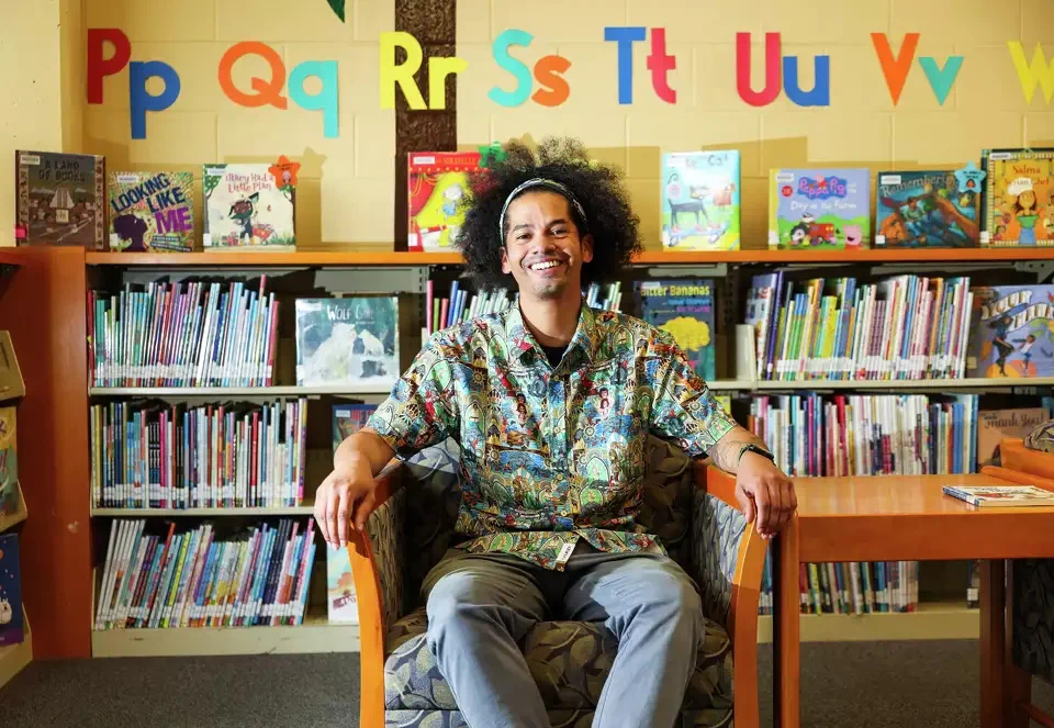 Librarian Mychal Threets sits smiling in the children's section of the Solano Public Library