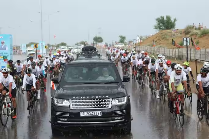 KanchanGupta's tweet photo. Prime Minister Modi's convoy amid cyclists in rain during a roadshow in Bikaner, Rajasthan.

#ModiMoment 21 https://t.co/iphV3OH0dG