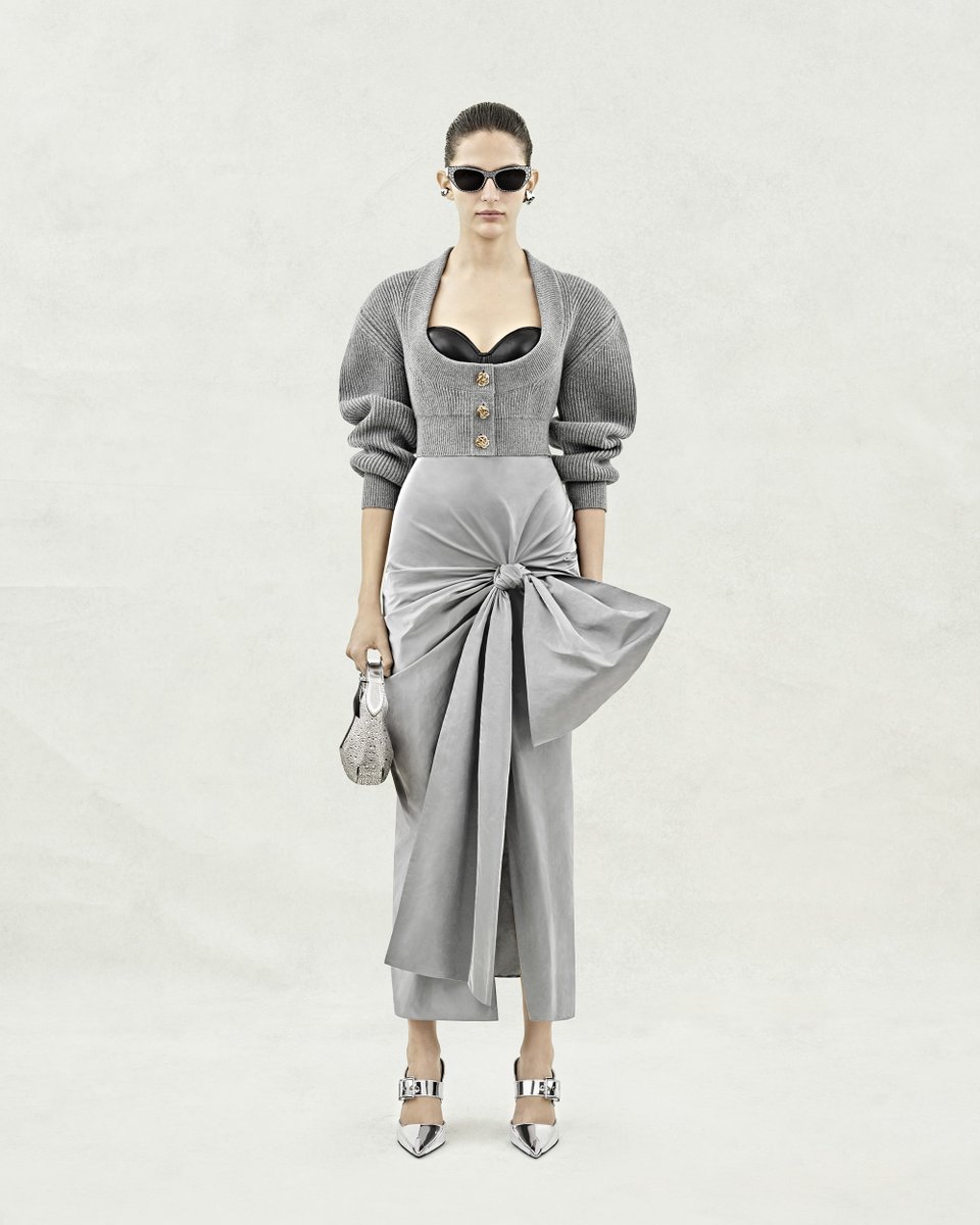 McQueen's tweet image. A pale grey cropped cardigan with gold metal knot buttons, a black corset with a sweetheart neckline and a silver knot drape skirt. Completed with a Mini #McQueenHoboBag with silver crystal embroidery.

Discover the #McQueenPreSS24 collection: on.alexandermcqueen.com/PreSS24_TW