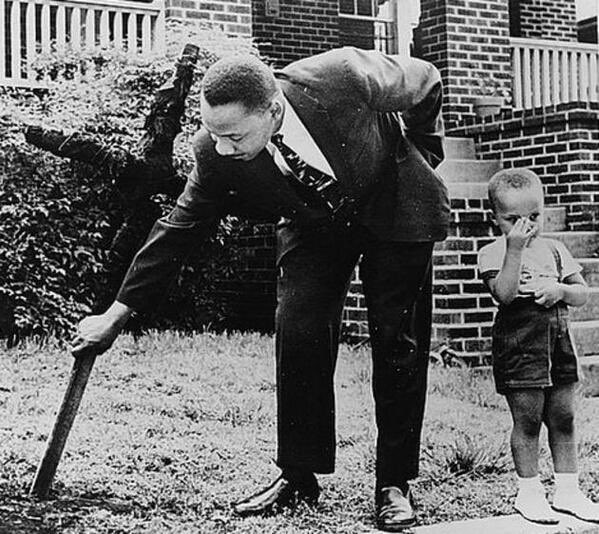 Martin Luther King pulls out burnt cross from his lawn in presence of his little son, Atlanta, 1960: