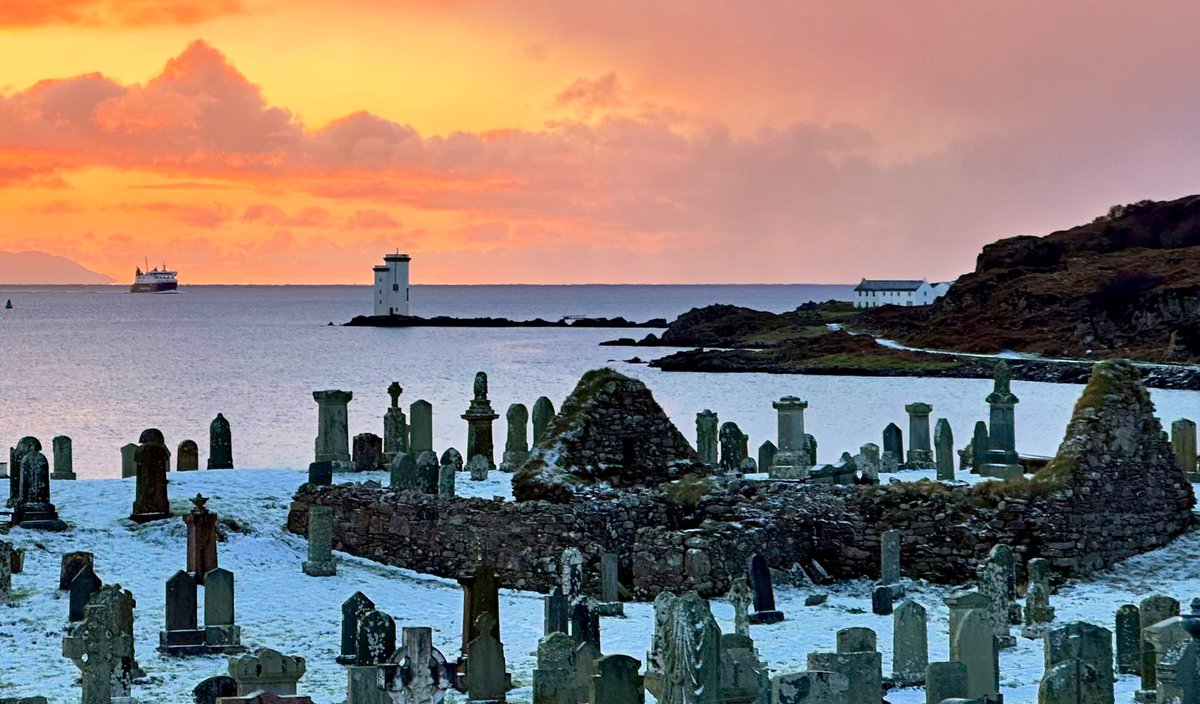 The ruins of the medieval chapel of St Nechtan and the old cemetery at Kilnaughton,  covered in a rare dusting of snow at sunrise this morning. Carraig Fhada lighthouse, <a href="/CalMacFerries/">CalMac Ferries</a> MV Finlaggan and the Mull of Kintyre in the background.
