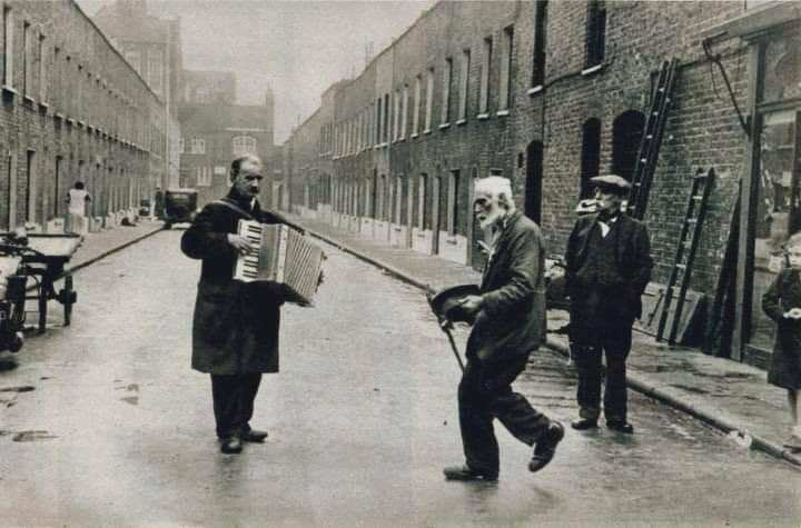 A photograph of a gentleman doing the 'Lambeth Walk' 
accompanied by accordionist in London 1938.
