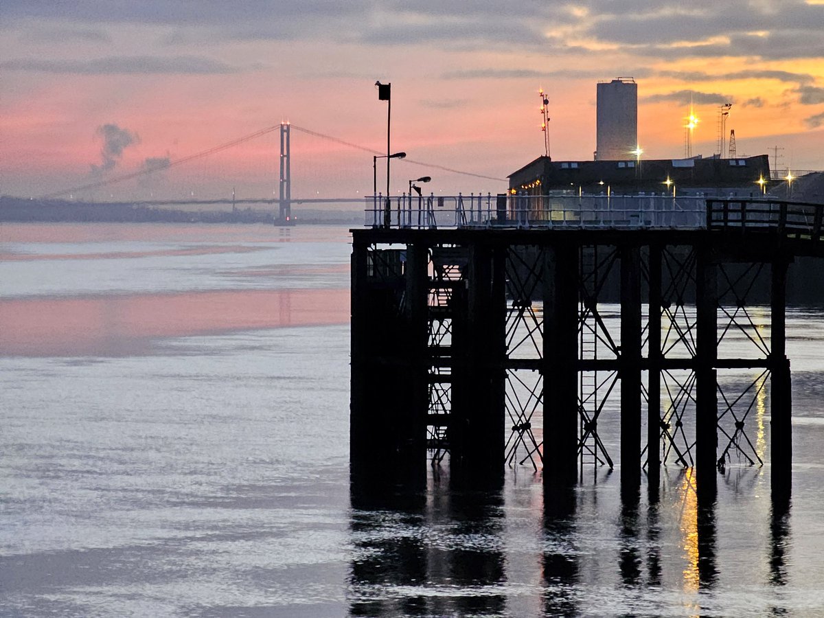 The Hull Pier in silhouette accompanied by <a href="/humberbridge/">humber bridge</a> and dusty pink sunset reflections! A very calm but chilly Estuary tonight. #Hull ❤️