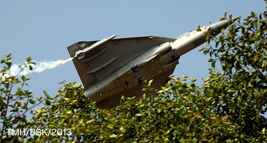 writetake's tweet photo. #TejasDay 🇮🇳

An iconic pic of #Tejas shot by #BSK, taken from the Media Centre at AFS-Y during #AeroIndia 2013. An image that ideally captures the #LCA story -- literally coming out of the woods, blowing away the doubters. I've been sharing this every year on Jan 4, an image etched in my heart with loads of emotions. That's all from my hangars today. Hope you folks enjoyed the updates. 😊 #avgeeks