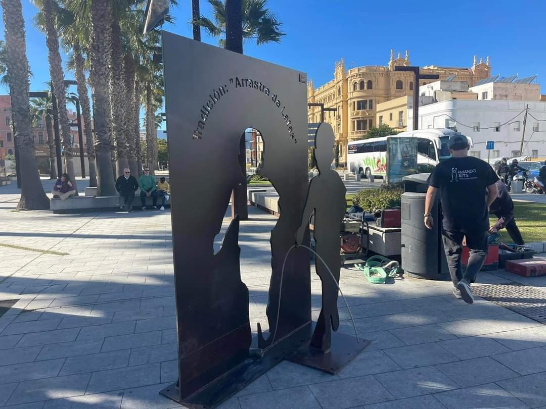 La escultura homenaje al Arrastre de latas, así como tres murales, se ubican en el Barrio de la Caridad, porque forman parte del I Festival de Arte Urbano, cofinanciado con Fondos Europeos de la Estrategia DUSI, que tiene por objetivo la revitalización del Barrio de la Caridad.