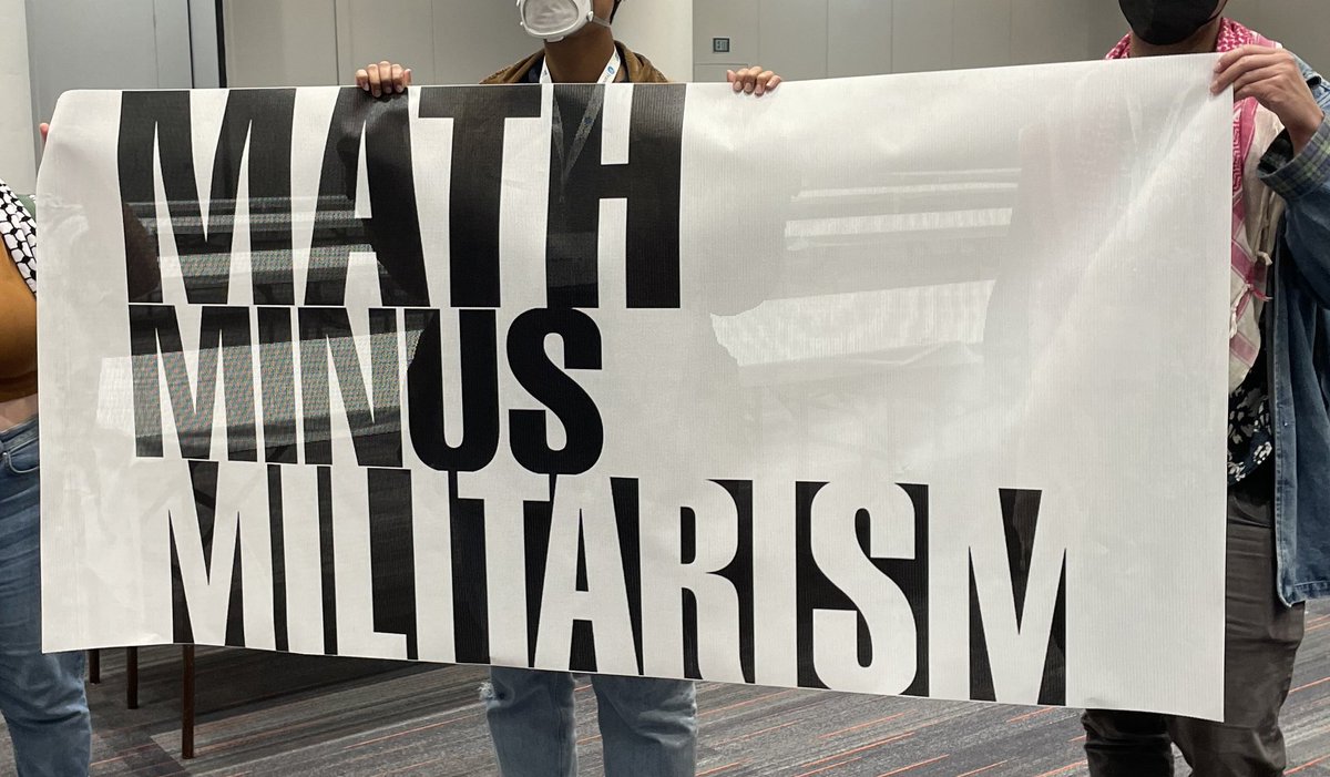jm_collective's tweet photo. Conference goers at #JMM2024 are standing up for a  #MathMinusMilitarism. While the JMM welcomes the NSA to recruit mathematicians for secrecy and surveillance, we refuse to use our labor to aid and abet war and imperialism! https://t.co/au1tZbWPBM