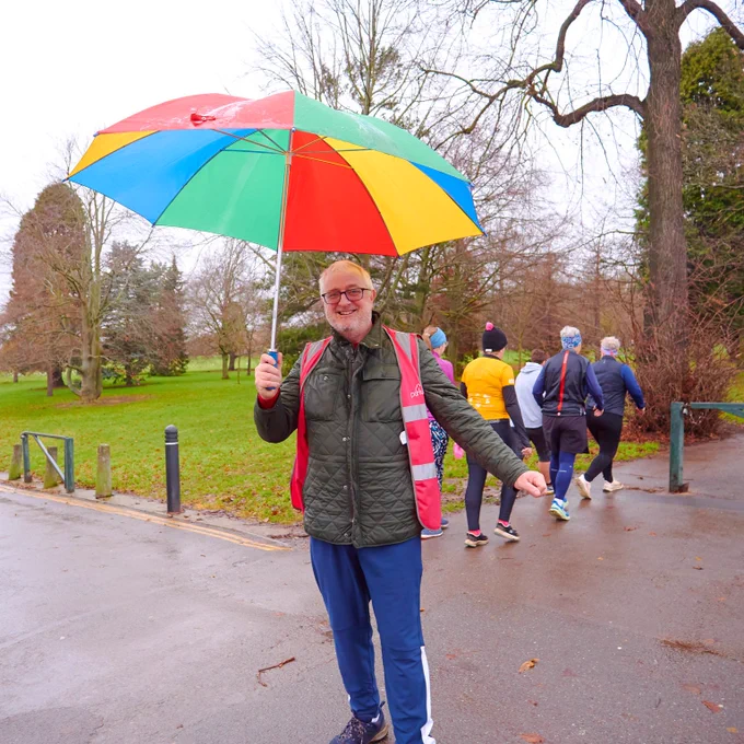 Image of parkrun volunteer holding an umbrella up at an event
