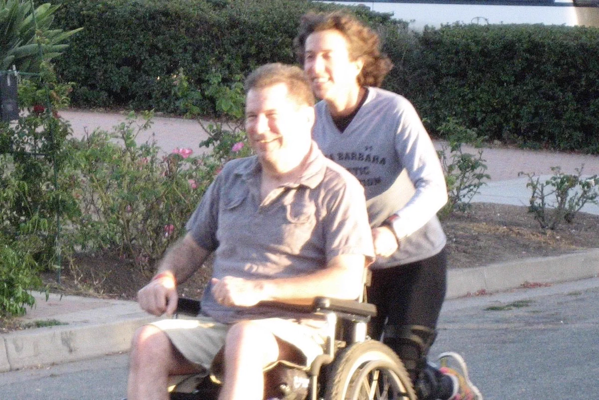 Hal and Fran Finney out on a run together, with Fran pushing Hal in his wheelchair.