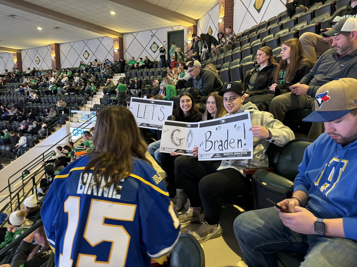 Sitting next to <a href="/CameronBirnie/">Cameron Birnie</a> and <a href="/LeahBirnie/">Leah Birnie</a> - Braden Birnie’s parents. There’s about 80 family and friends here making the trek to Grand Forks. Love to see it!