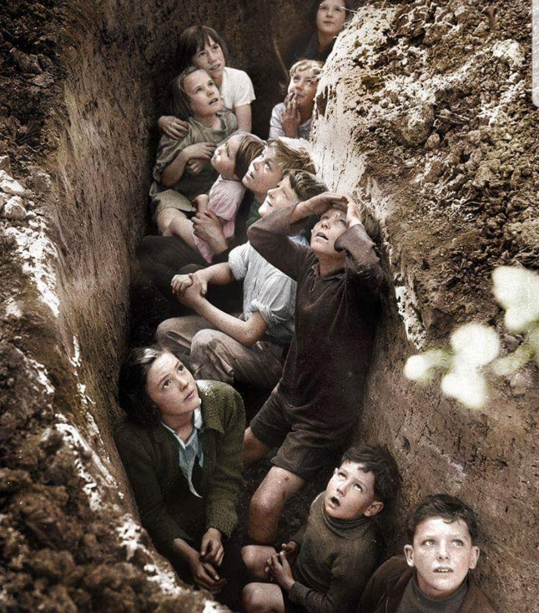 WW2Facts's tweet photo. British children taking shelter in a trench while watching an aerial battle overhead during the Battle of Britain on September 3, 1940.

#History #WWII https://t.co/PQeyUMu1cY