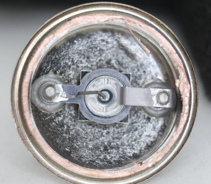 Top view of a transistor in a circular metal case. The internal components are visible, rings connected to pins.