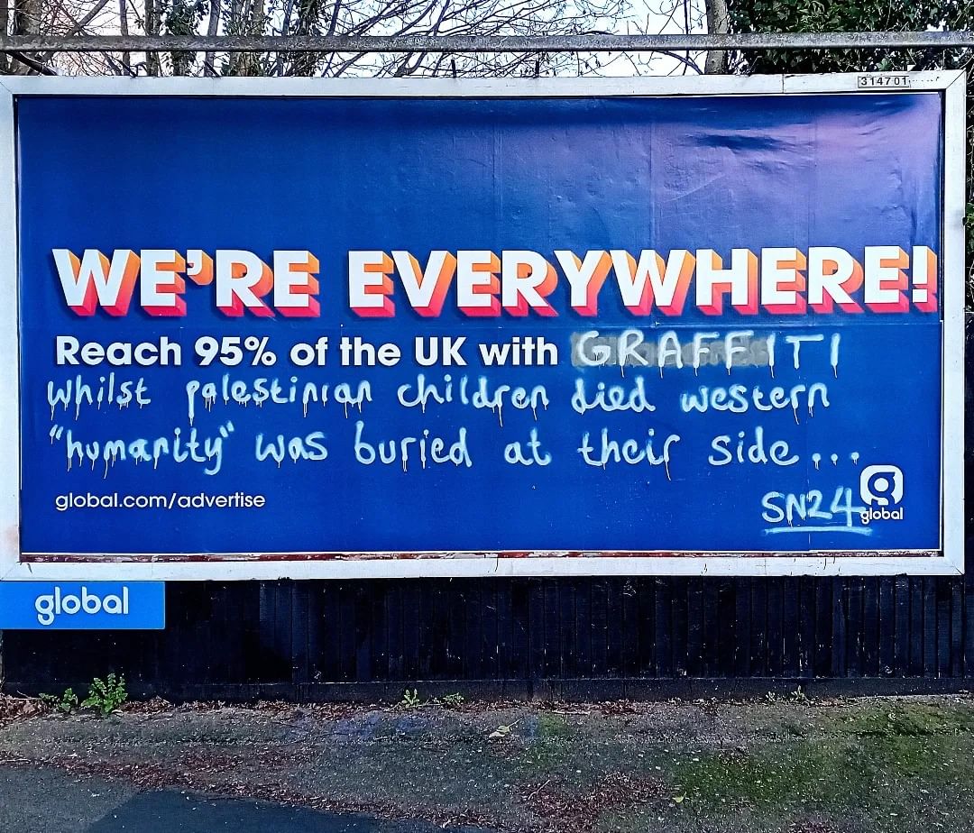 GraffitiRadical's tweet photo. "Reach 95% of the UK with graffiti.
Whilst Palestinian children died, Western"humanity" was buried at their side..."

Billboard graffiti seen in London https://t.co/gJ0nnLnUT5