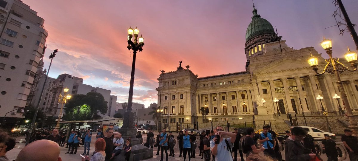 patmalanca's tweet photo. Sobre un cielo rosado la Policía vigilante y los infiltrados se recortan en el horizonte del Congreso detrás de cineastas, pintores, actores, músicos, gestores Culturales que reclaman que se eviten los recortes en Cultura. https://t.co/4WPs0qb0oa
