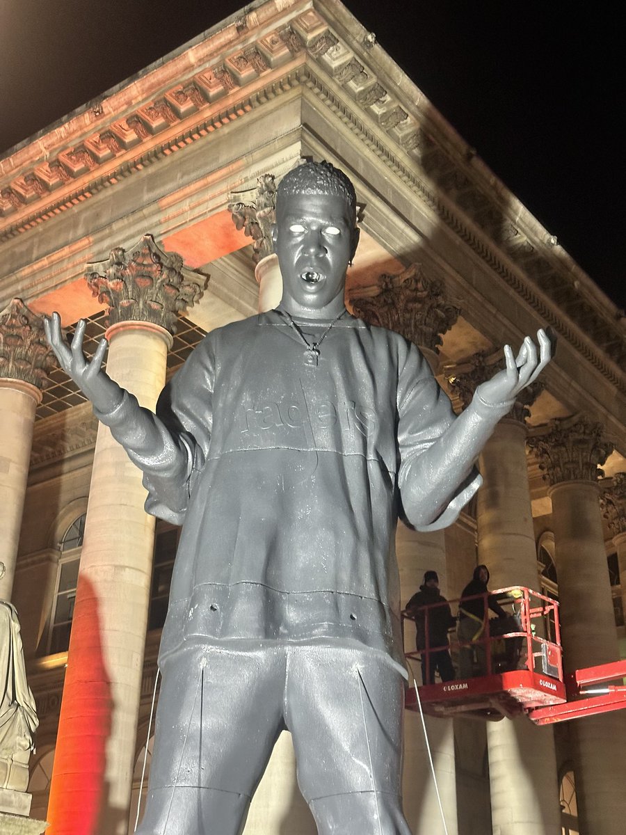 andrepitie's tweet photo. Who is this ? Who made this massive statue ? Paris Bourse (former stock exchange building) tonight, France. Nike Air shoes, Raders logo on the T-shirt. https://t.co/xuMR6NrwJF