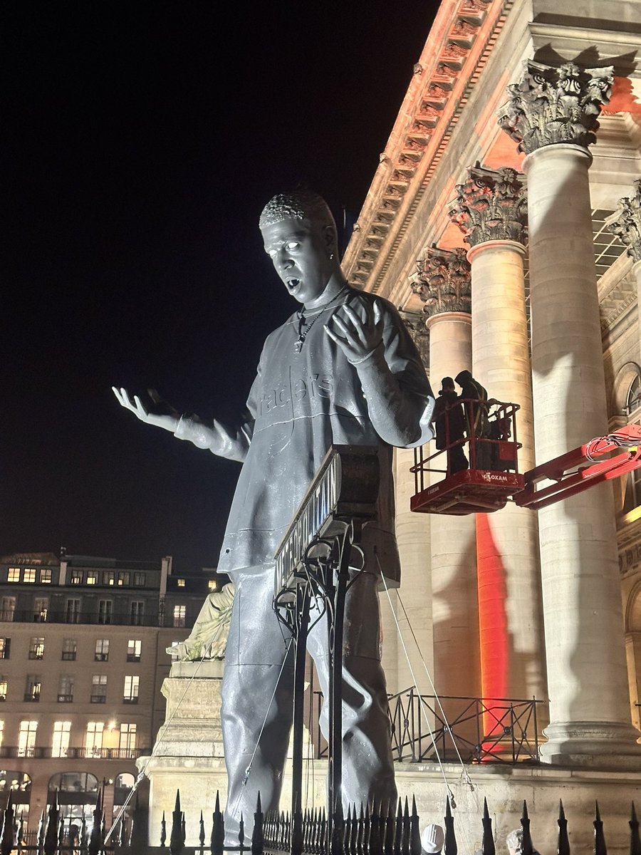 andrepitie's tweet photo. Who is this ? Who made this massive statue ? Paris Bourse (former stock exchange building) tonight, France. Nike Air shoes, Raders logo on the T-shirt. https://t.co/xuMR6NrwJF