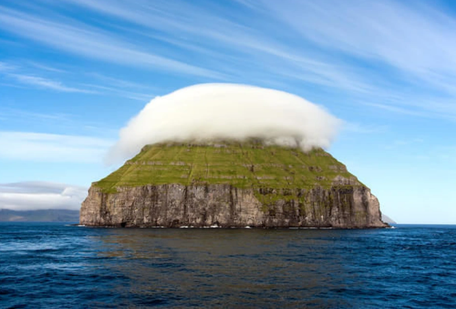 r_fatin's tweet photo. Invisible shades surround the top of the island and become visible when the air temperature reaches the dew point. These stationary clouds are no joke and are essentially a sign of turbulent air, so pilots will tend to avoid this area.

Looking from a distance, the island looks like it is "wearing clouds" above its head, located in the middle of the vast ocean.

Currently, only seabirds live on the island. In the summer, this place has about 300 sheep brought by people in Hvalba (Suðuroy island) to release on the pasture, but when winter comes, they come to bring the sheep back. To look after the sheep,