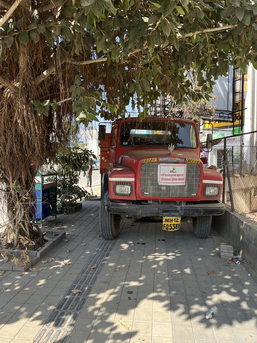 rakesh1908's tweet photo. PMC duty truck on footpath resting under the tree and people walking on the road under the sun. This is near Sreenivas Classic Baner Road. #PMC https://t.co/mkSmKLJn6b