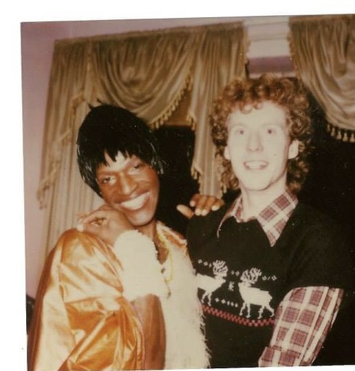 Here's a rare photo of Marsha P. Johnson with fabulous hair, wearing a beautiful and unique outfit, and sporting a radiant smile. The identity of the person next to her in the photo is unknown. Credit goes to the photographer, and the date of the photo is also unknown. 📸