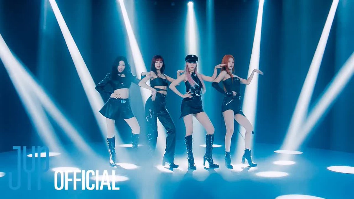 Four members of the K-pop group ITZY pose on a stage illuminated by bright blue spotlights, wearing black leather outfits, with the watermark 'ITZY OFFICIAL' visible in the bottom left.