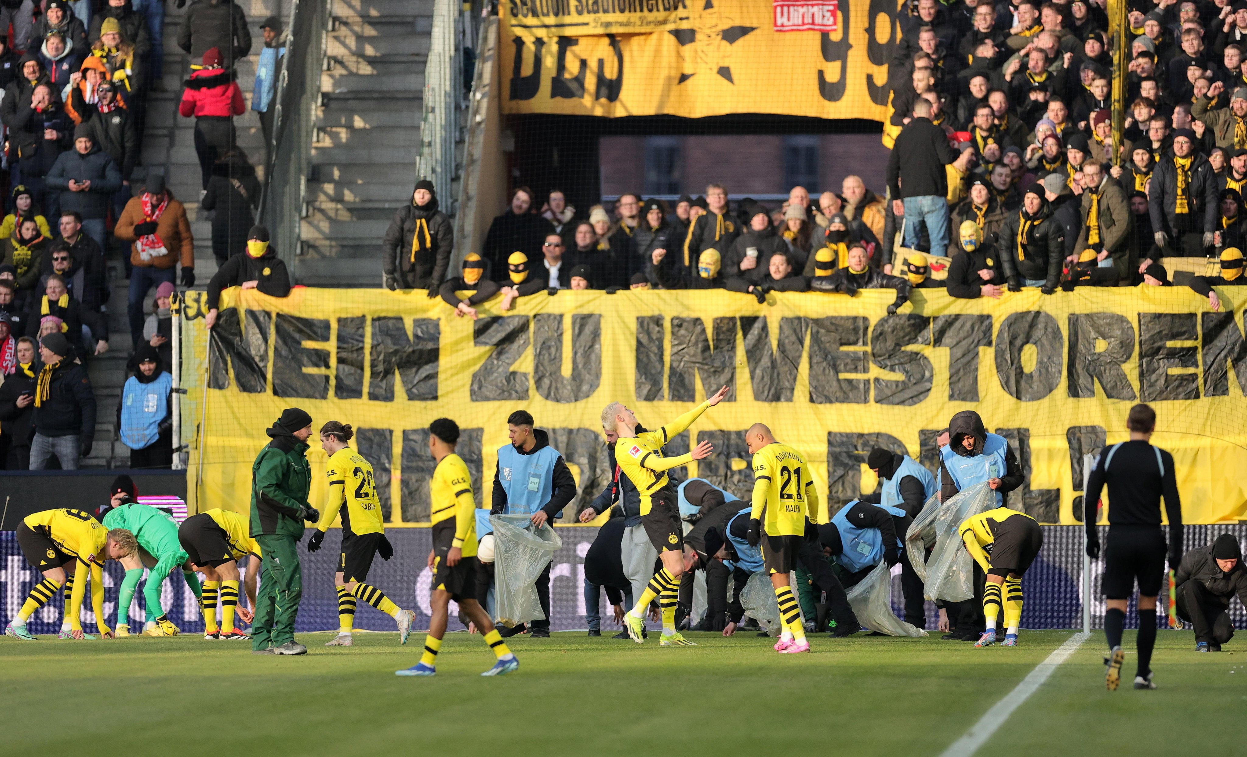 Los jugadores del Dortmund ayudan a recoger las monedas.