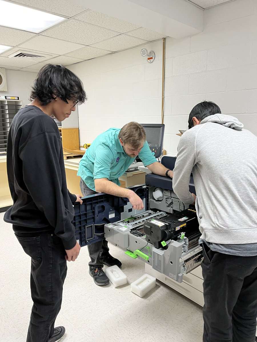 A new semester, new Help Desk students! Here our IT tech is showing two students how to replace broken parts on the copier.