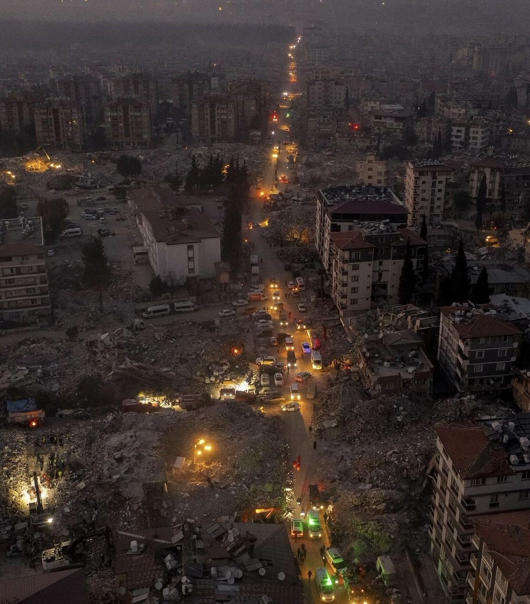 Enkazlar içinde kalmış bir kenti aydınlatan araba ışıkları..