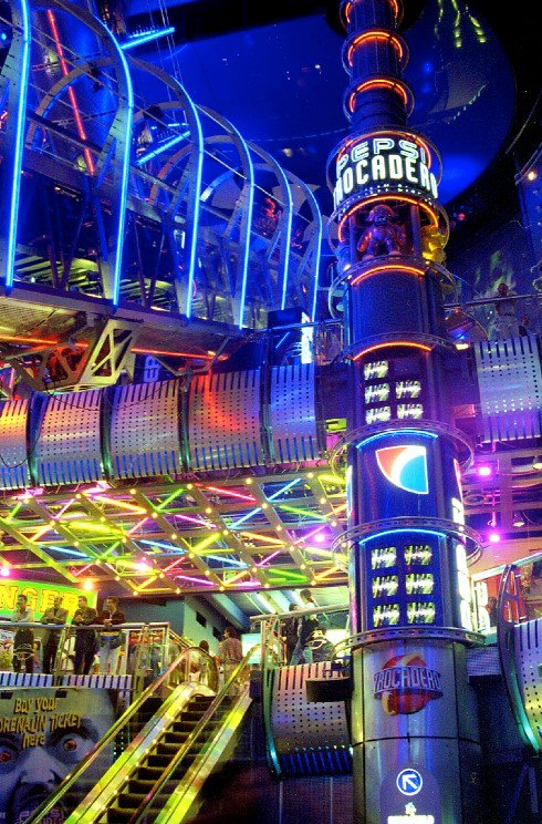 GuyFawkesRetro's tweet photo. I've tried explaining gaming arcades to my eight year old son. He's aware of them, but not in the way you'd think. 

Arcades these days are basically ticket pushing machines, get points, get tickets, get a stylafoam airplane from the booth. 

I showed him pictures of SEGA World / Pepsi World in London from the 90's, The Trocadero. 

Then I showed him some footage. I can't explain the expression on his little face, but it was one of some confusion and 'happiness'. 

Obviously, he had questions. Strange questions.

'Did they sell Prime?' no, I said. 

'46 flavours of Pepsi' I said.

'What if you ran out of money' well,  you watched other people, I said. 

'All those lights and noise. I bet people had a headache!'

Erm, 'Yes, I guess'. I said. 

For me, the Trocadero as it was back then, SEGA / Pepsi world was the pinnacle of our times. The future of things to come. Gaming in its highest form. Lights, music and every flavour of Pepsi known to humans. Socialising, Alien Wars, a DJ and VR. A place to hang out, make new friends and watch some of the greatest Street Fighter II players I've ever seen.

But it's gone now. There's nothing like it anymore. Arcades now are considered Niche, they are for corporate events and office Christmas parties with that one bloke who shouts 'Oh wow look, Mortal Fighter and Daytona Rally 2!" whilst you wait 45 minutes in a queue for a vegan hotdog. 

My son thought the photos and the footage I showed him *was* absolutely out of this world. He really thought it was something from a film, a make belief place full life, lights and noise.

A different world.

He has asked if we can go, but I had to break it to him gently.

'It was 30 years ago, in the nineties. Things have moved on, for the better. You can play all of these games at home online with your friends 'PrimeApex560XXb' & 'MilfMoleJerry5' in the warm, can't you.' 

Although he's only 8, I think the penny dropped. 

#EggsAndSpam #SEGA