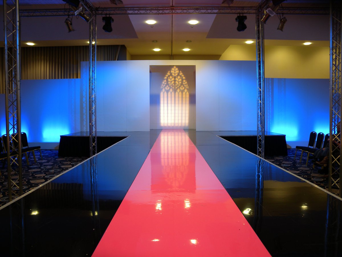 Stunning Stage Build Catwalk for a Fashion Show, designed with a impressive high gloss finish which reflects the light and adds glamour to your event, including LED uplighters to customise the colour of the backdrops. #stagehire #events #stagebuild #catwalk #fashionshow #hire
