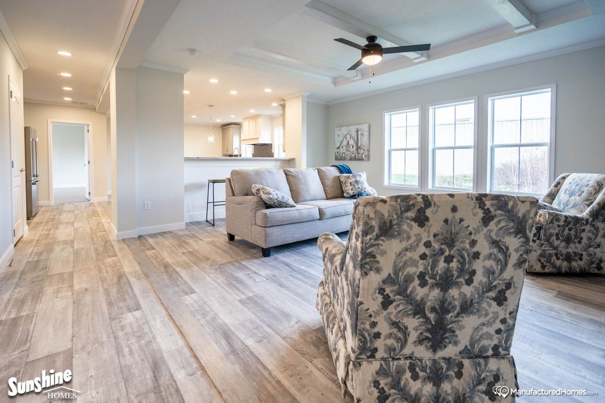 Picture a living room where charm meets comfort. 

A cobblestone wall features a built-in fireplace, creating a cozy focal point. The open floor space ideal for gatherings, complemented by a tray ceiling adding a touch of elegance. 

Explore this at myfloridamanufacturedhome.com/manufacturer/2…