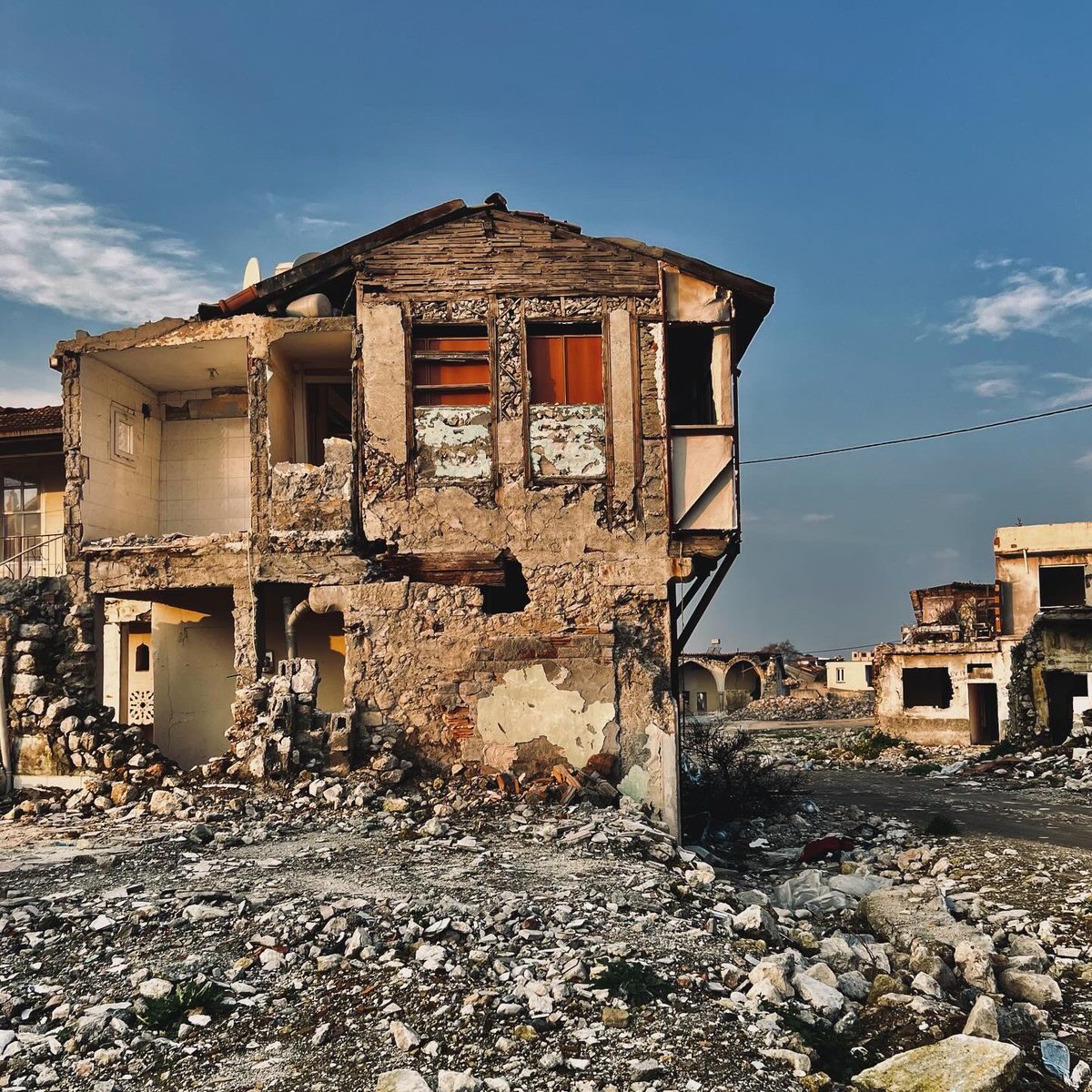 Mavihaller's tweet photo. Eski Antakya sokaklarında herkes davalı, herkes davacı, herkes birbirine notlar yazıyor betonlar, binalar üzerinden. Serzenişte bulunanlar, dava dosyası numaraları yazanlar, “yan binayı yıkarken benimkini de yıkmaması için daha ne yapabilirim” diye çabalayanlar, devlet evlerini rezerve katıp rant denizine sürüklemesin diye her yerde yazılar işaretler oklar. Faydası olacaksa tabii.