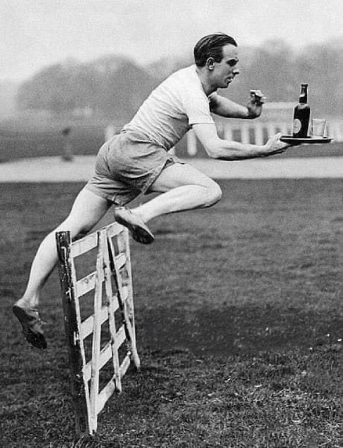 El corredor de vallas británico Percy Hodge demuestra el salto de obstáculos perfecto mientras lleva una botella y un vaso en una bandeja. Percy Hodge se convirtió en campeón olímpico en los 3.000 metros con vallas en 1920.