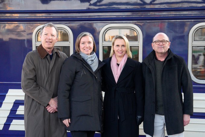 Ambassador Brink stands with Inspectors General in front of a railway car. 