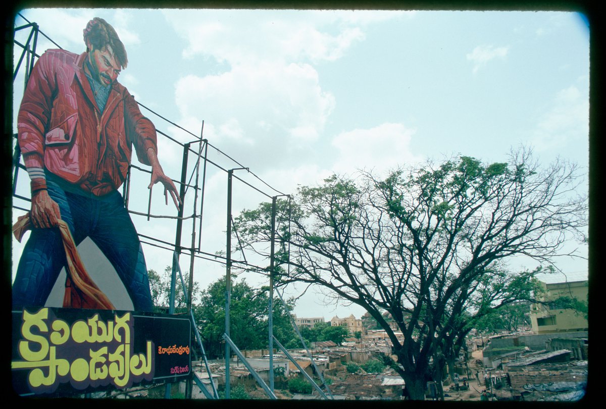 View of the painted poster of the film 'Kaliyuga Pandavulu' looming over the slum near Lakdi ka Pul, 1986. #Hyderabad