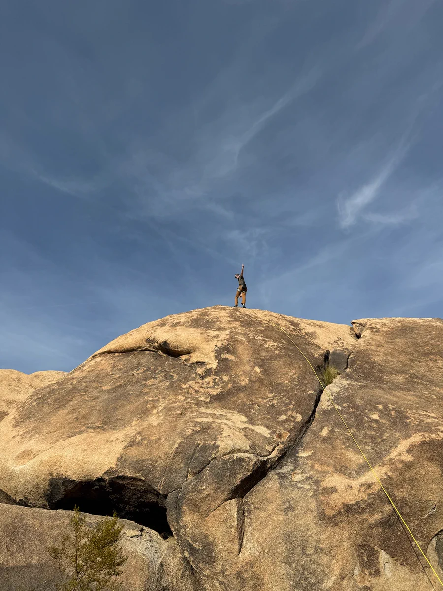 Me on top of a 40-foot granite rock giving a thumbs up, ready to lower on a climbing rope