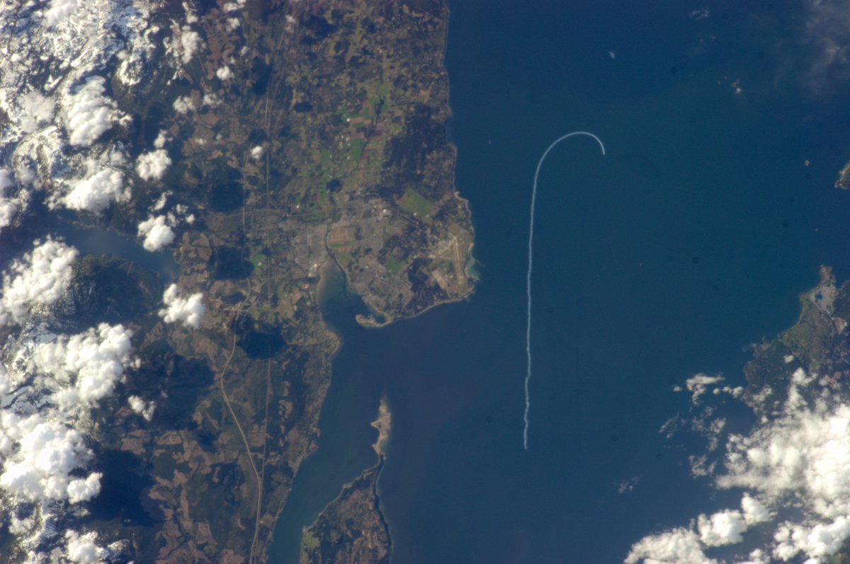 Cmdr_Hadfield's tweet photo. The only time I saw something moving on Earth - a picture from my spaceship of the @CFSnowbirds aerobatic team, their signature white smoke visible over the blue of the Strait of Georgia, by Comox. https://t.co/9paiHdZWCC