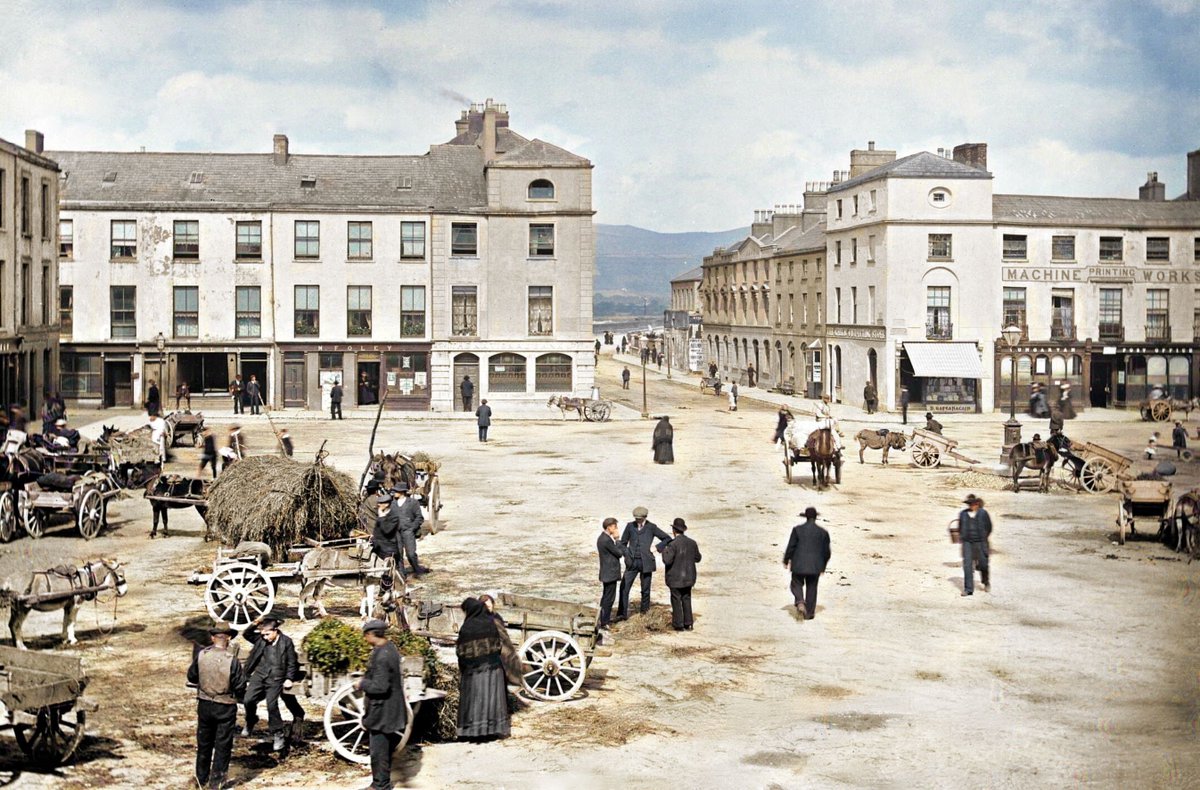 c1890, Dungarvan Past Grattan Square in Dungarvan, Co. Waterford, is alive in a colourful slice of history, captured by Robert French. Horse-drawn carriages & townsfolk mingle in the commercial heart of the town. What catches your eye? 📷 NLI #Waterford #Dungarvan #Colourised