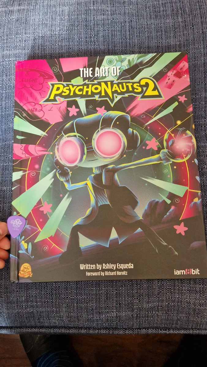 Jamiepwest's tweet photo. @iam8bit @DoubleFine @AshleyEsqueda Holy Macaroni!! The Art Of Psychonauts 2 just arrived! I have a lot of beautiful art books but this one might be THE most beautiful. Wow. Great work! (Guitar pick included for scale) https://t.co/XpxmLTRcgy
