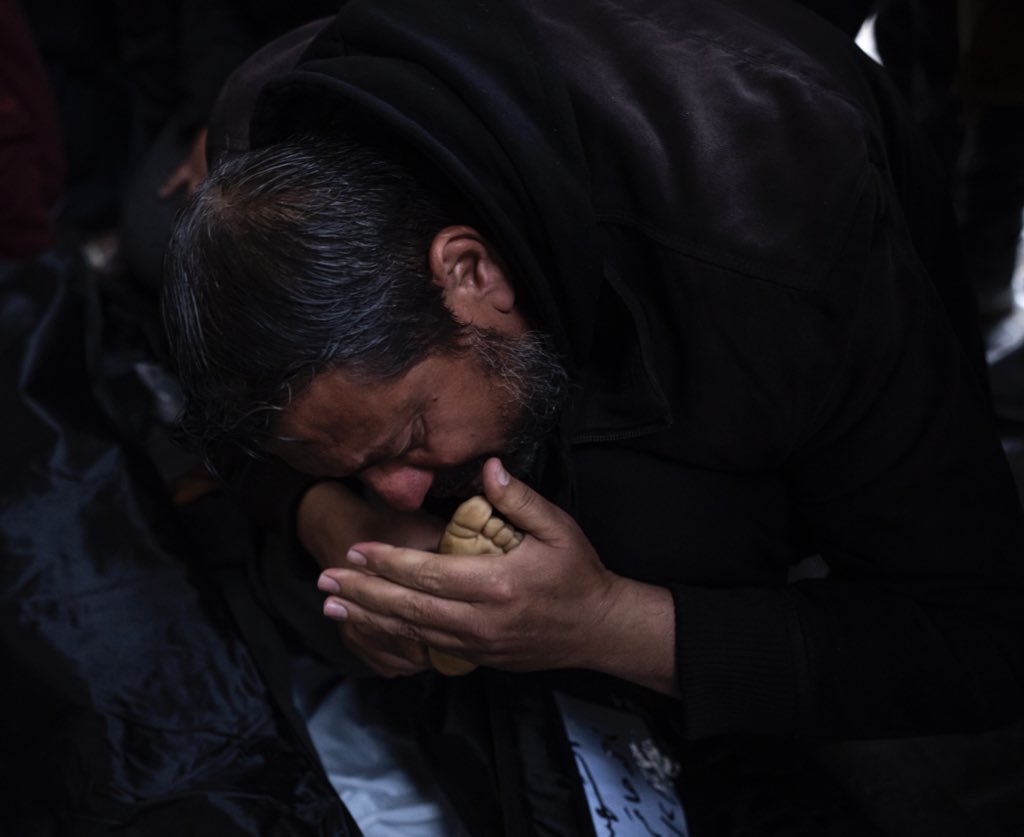 A Palestinian man kisses the foot of his dead son, who was killed in the Israeli bombardment of the Gaza Strip, outside a morgue in Rafah, southern Gaza. (AP Photo/Fatima Shbair)