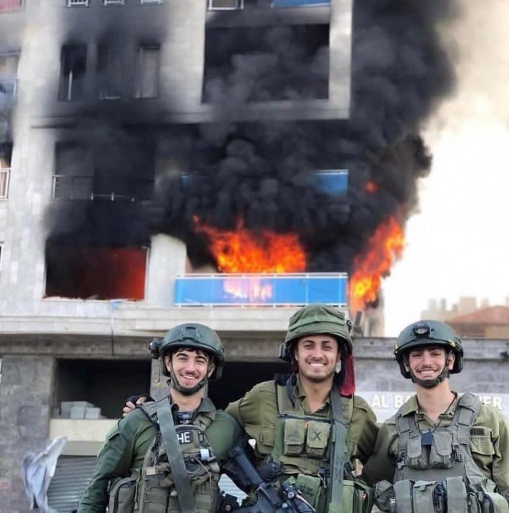 The building burning in the background is the European Mediterranean Center for Human Rights . Israeli Terrorist Occupation Forces take selfies while committing genocide . 

#decoloniseeverything #ꜰʀᴇᴇᴅᴏᴍ #StopBombingCivilians #indegenouspeople #stopcolonisation #revolution…