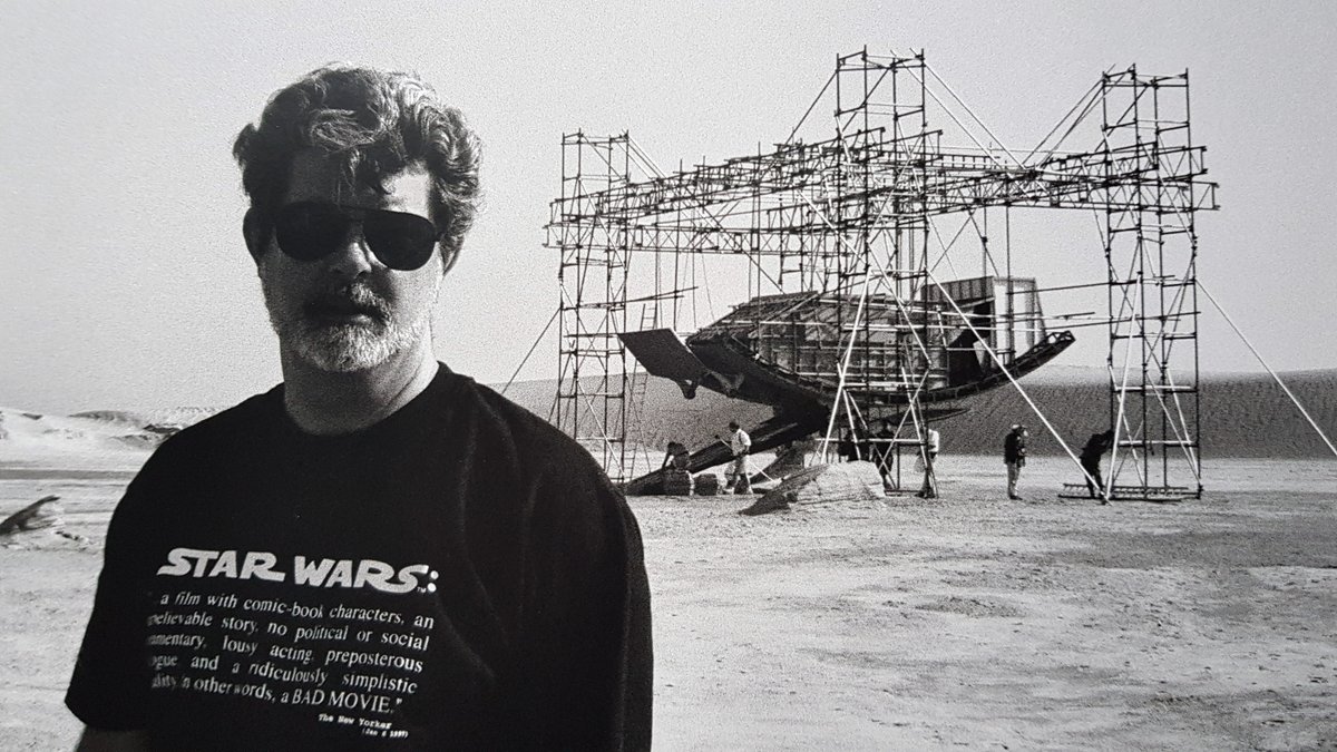 GEORGE LUCAS filming The Phantom Menace with a t-shirt with the New Yorker's review of STAR WARS: Comic-book characters, unbelievable story, no political or social commentary, lousy acting, preposterous dialogue, a ridiculously simplistic morality. In other words, a BAD MOVIE.