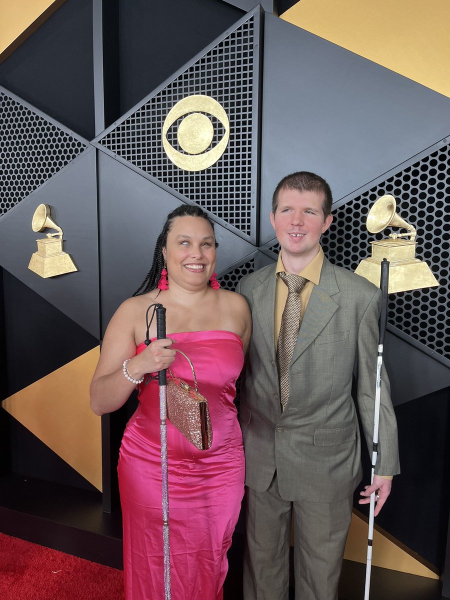 First time  amplifying disability culture with   @rampdup    on the red carpet!  #Grammys #RAMPD #adelante  ID: Precious and @ShaneLowe1 smiling together in front of a Grammys backdrop on the red carpet. Precious is holding her pink  glam   cane and wearing a strapless pink gown.