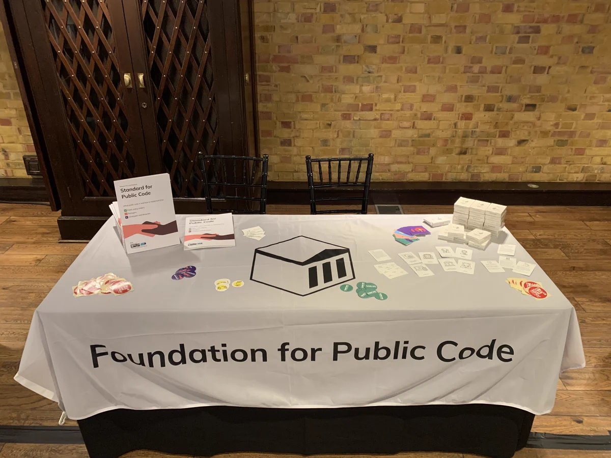 The Foundation for Public Code table at the conference. On this table are copies of Standard for Public Code, Governance Game, and stickers from the Foundation. Grab them.